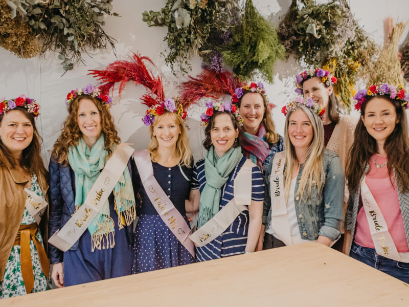 Group of bridesmaids and bride wearing sashes and flower crowns.jpg